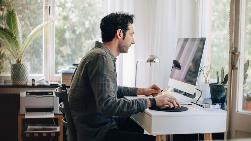 A man using his computer at his desk at home. 