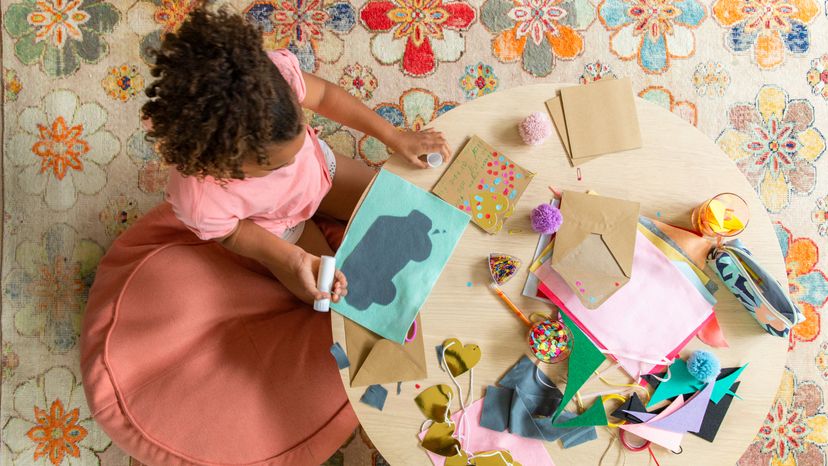 An overhead view of a little girl making paper art. 