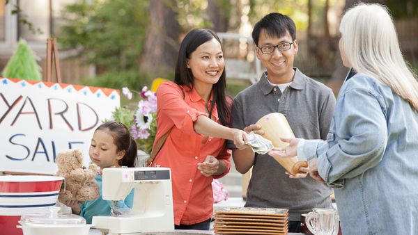 An Asian family paying for an item they purchased at a yard sale. 