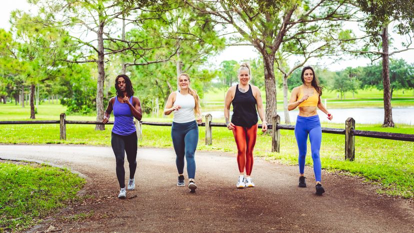 A group of women power walking down a park. 