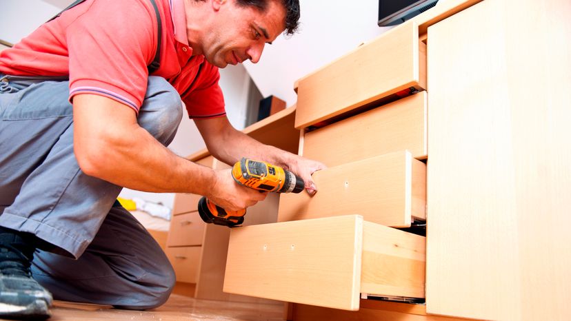 A man assembling a wooden drawer with tools. 