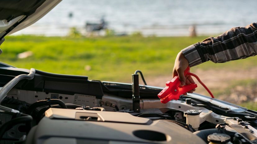 A man using jump cables to start his car battery. 