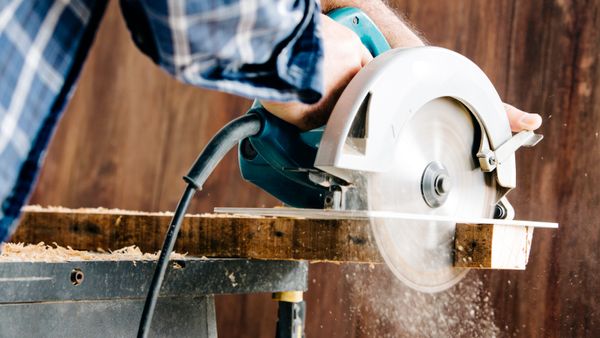 A male carpenter using a circular saw in his home workshop. 