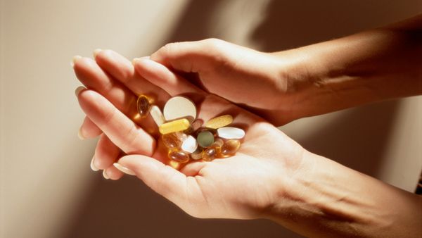 A woman holding different vitamin capsules and pills. 