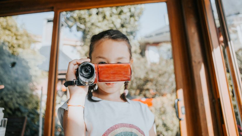 A little girl using a video camera to film her family. 