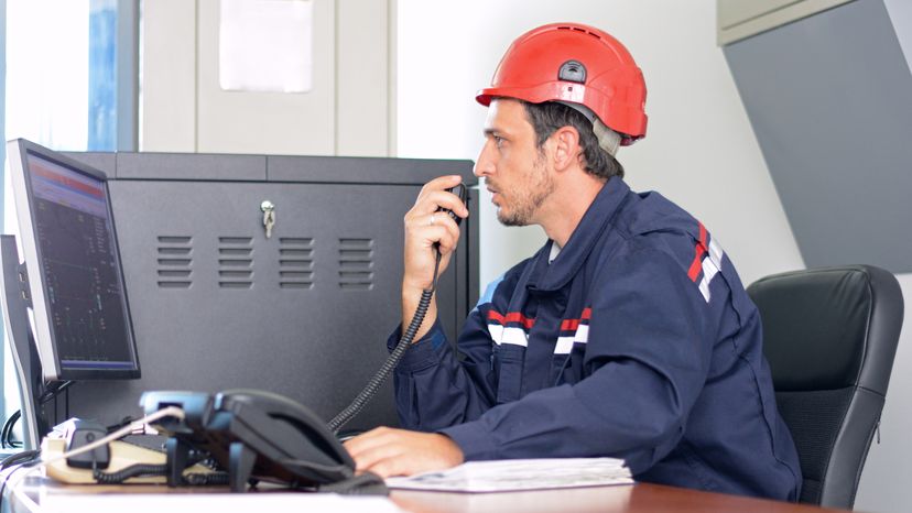 An engineer wearing protective work gear and talking into a cb radio.