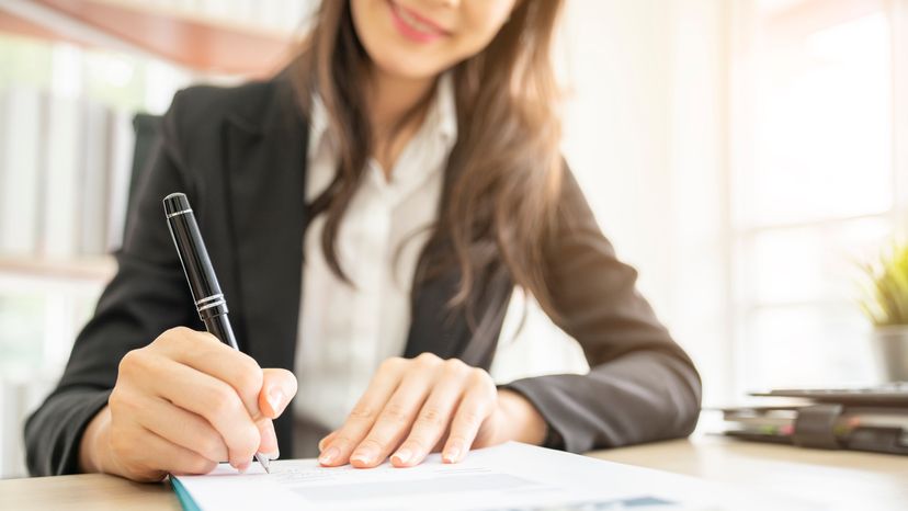 A business woman using a ball point pen to write.