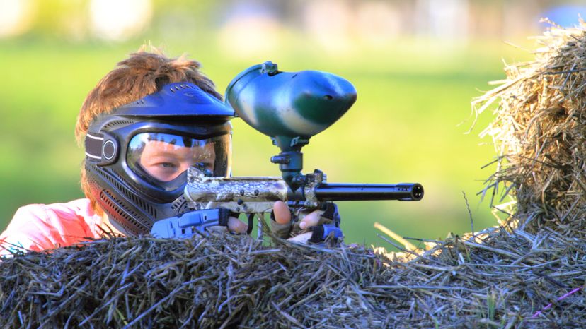 A young boy playing with a paint ball gun. 