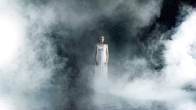 A woman standing on a stage surrounded with fog.