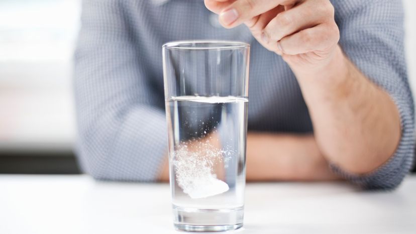 A man dropping a dissolvable tablet into a cup of water. 