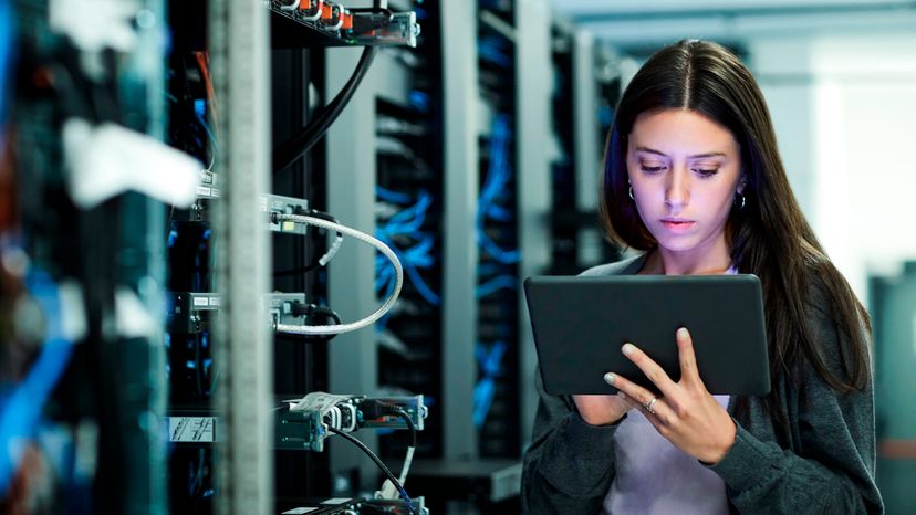 A female IT technician using a tablet in the server room. 