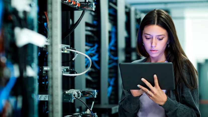 A female IT technician using a tablet in the server room.