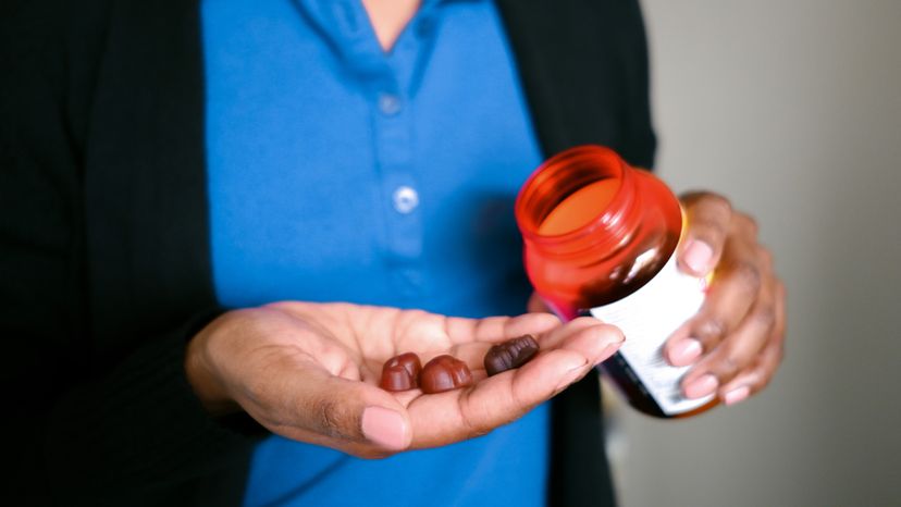 A woman holding fruit flavored multivitamins in form of gummy bears. 