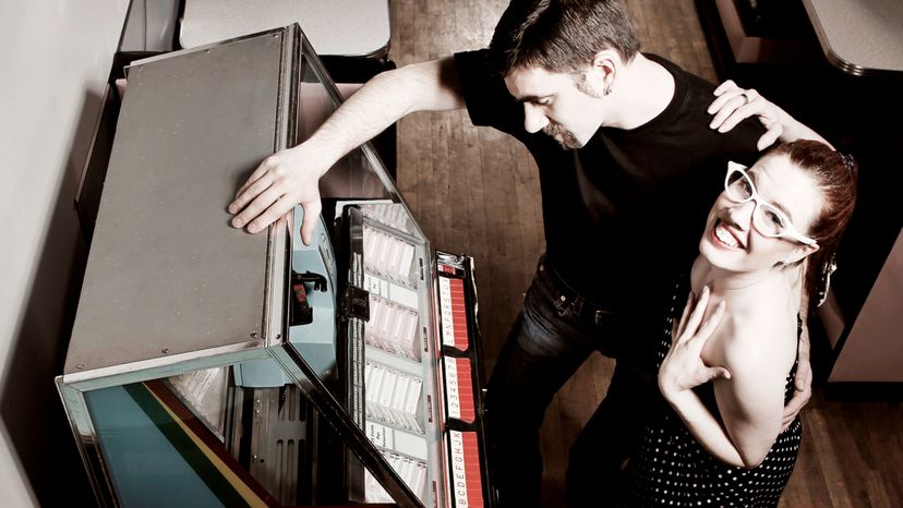 A retro couple choosing a song at the jukebox. 