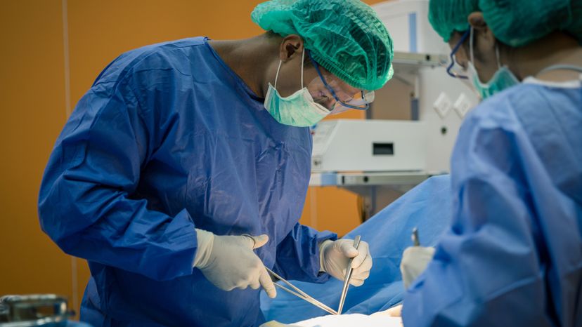 A doctor and a nurse preforming surgery on a patient. 