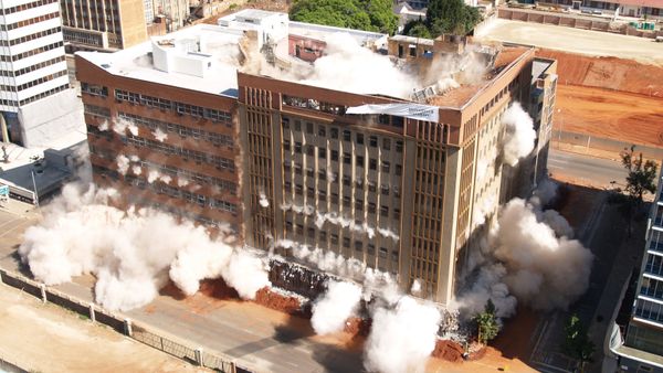 A building crashing to the ground due to being demolished by implosion 