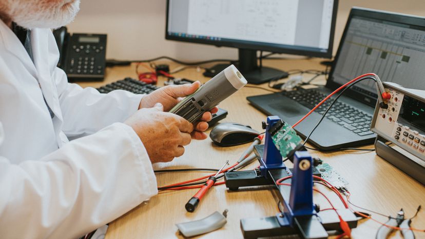 A scientist checking the battery compartment of an electronic device in his hand