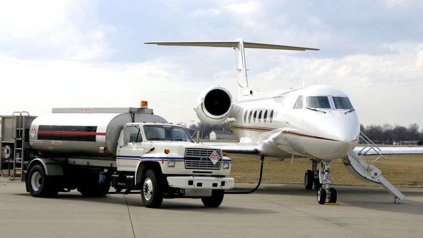 A private jet on a runway with a fuel truck parked beside it. 