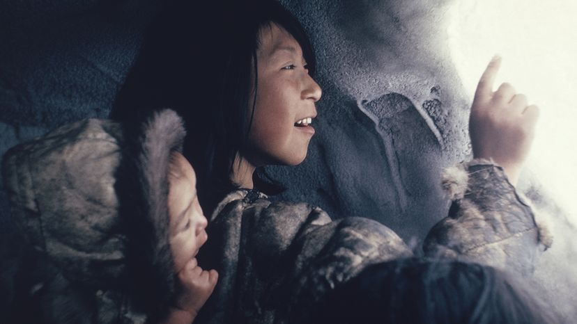  two young Inuit inside an igloo