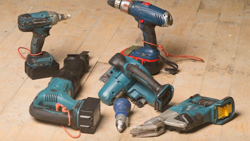 Different power tools placed on a wooden floor. 