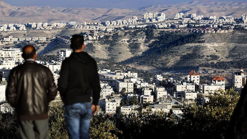 两名男子在观察以色列在巴勒斯坦西岸的马勒阿杜明定居点，背景是犹太沙漠。托马斯·考克斯/法新社/盖蒂图片社＂width=