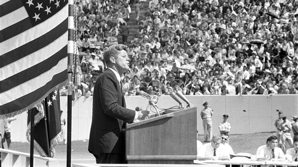 Men in black and white, outdoors, saluting American flag.