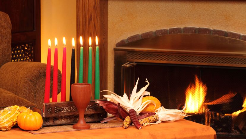 Kwanzaa candles on a table placed in front of a fire place. 