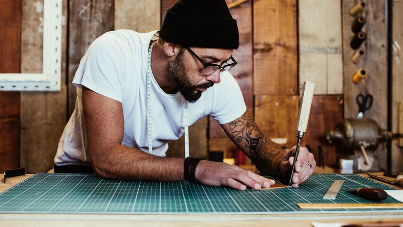 A man using his left hand to draw in his studio. 