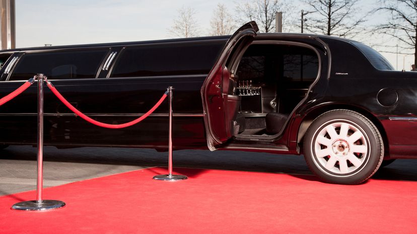 A parked limo with its door open in front of a red carpet. 
