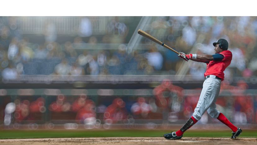 Baseball player holding a baseball bat with outstretched arms trying to hit a ball. 