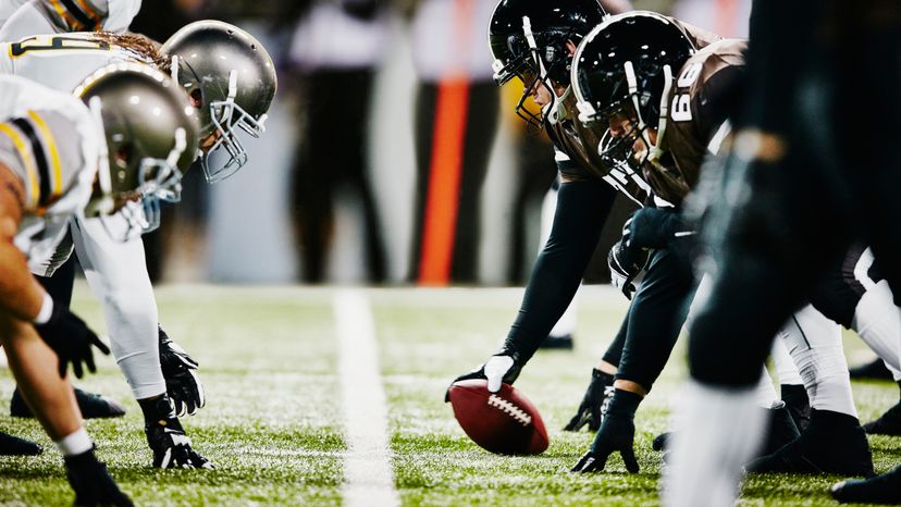 Two football teams on line of scrimmage during a night game.