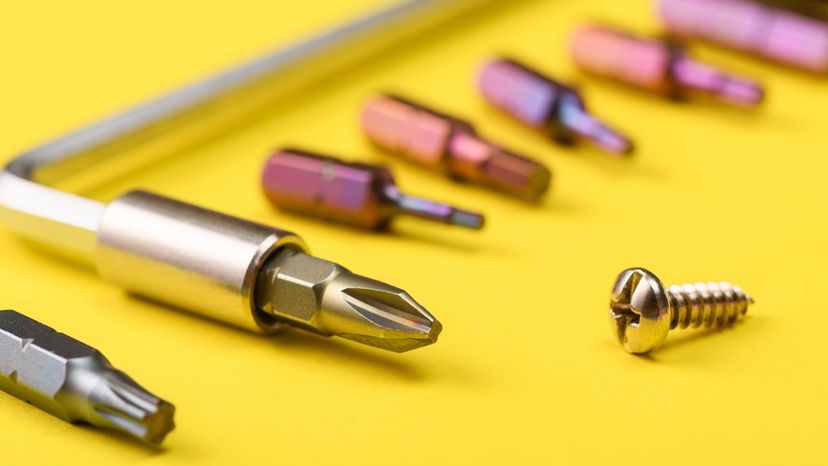 A screwdriver with different bit sizes arranged on a yellow material. 