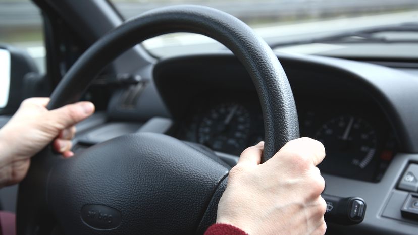 Two hands on a steering wheel. 