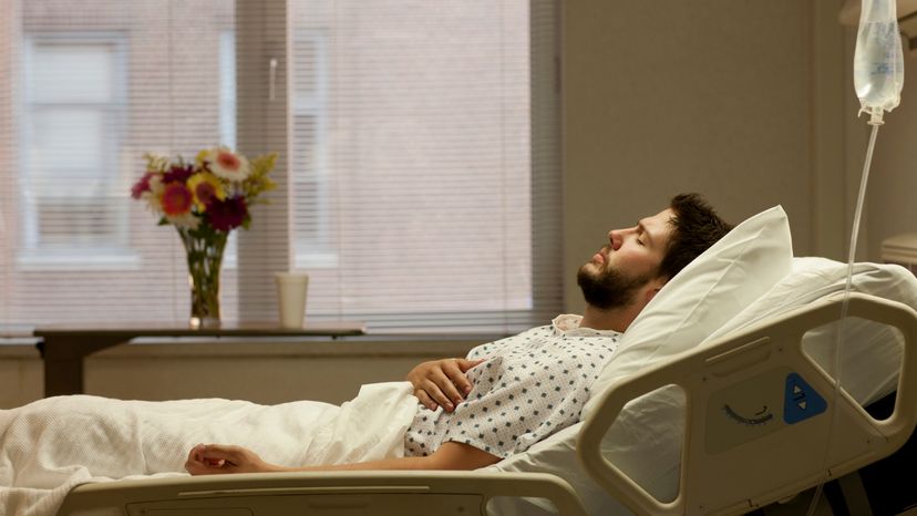 A man wearing a hospital gown, laying down in an hospital bed. 