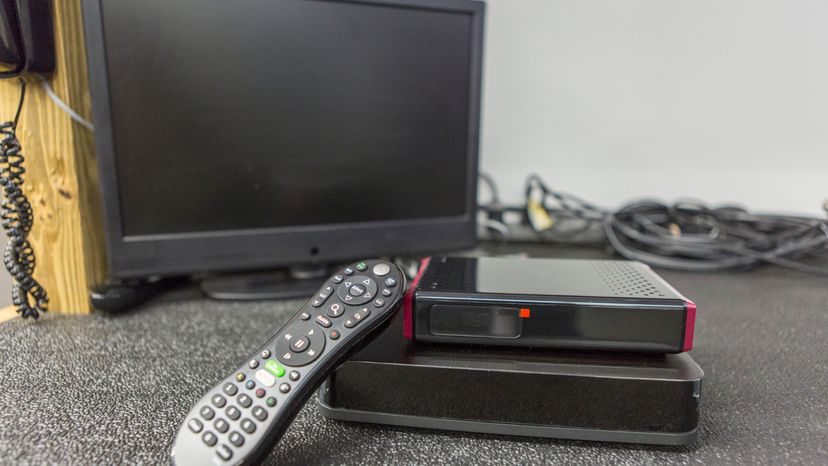 A TV remote in front a computer monitor. 