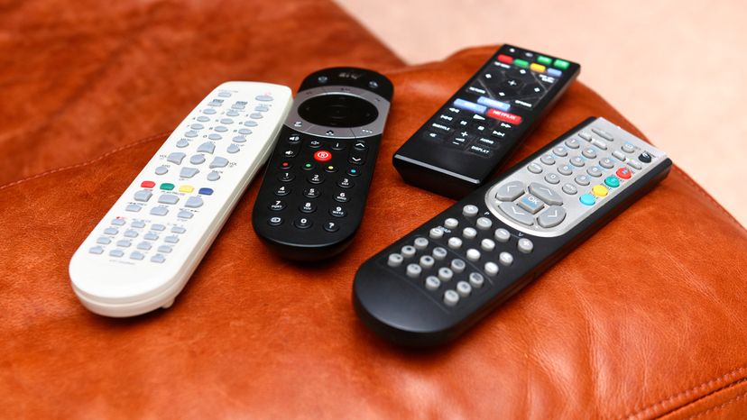 A close up image of four different remotes placed on a wooden table.