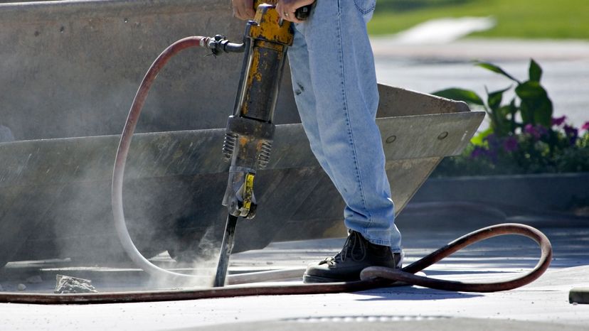 A man using a power drill on concrete. 