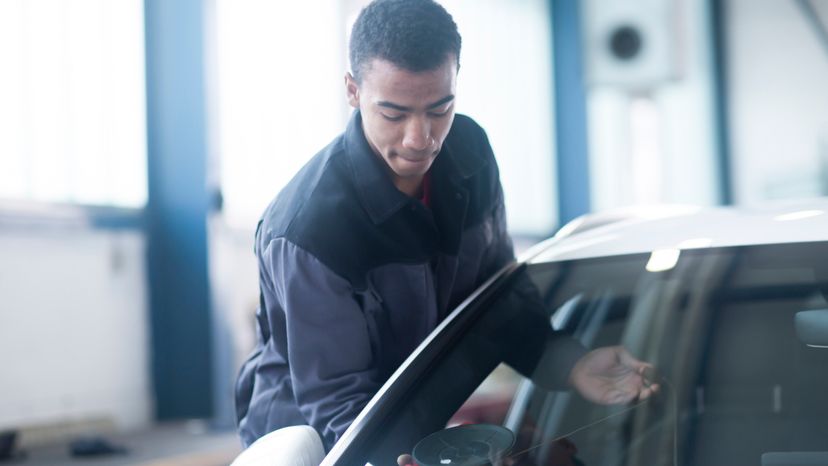 A man replacing a cars windshield. 