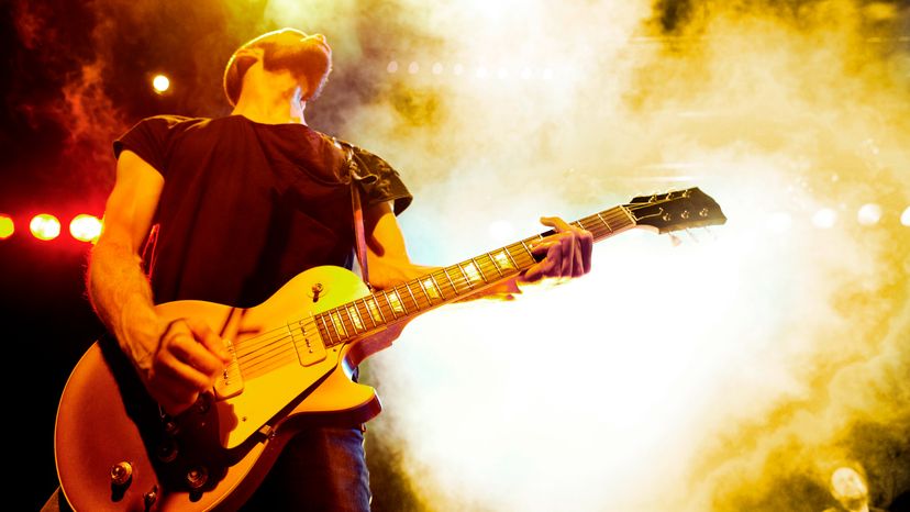 A rock guitarist performing on stage with smoke all around. 