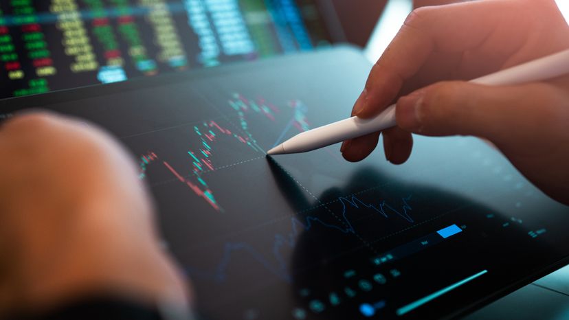 A hand using a digital pen to draw market analysis on a tablet.