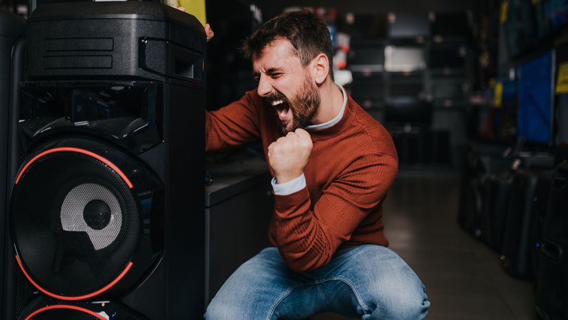 An excited man buying a music speaker in a tech store. 