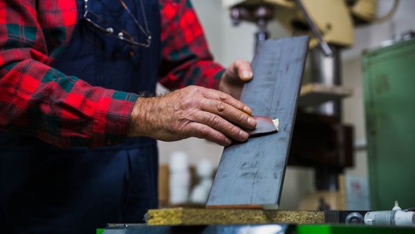 A man's hand sanding in the workshop.