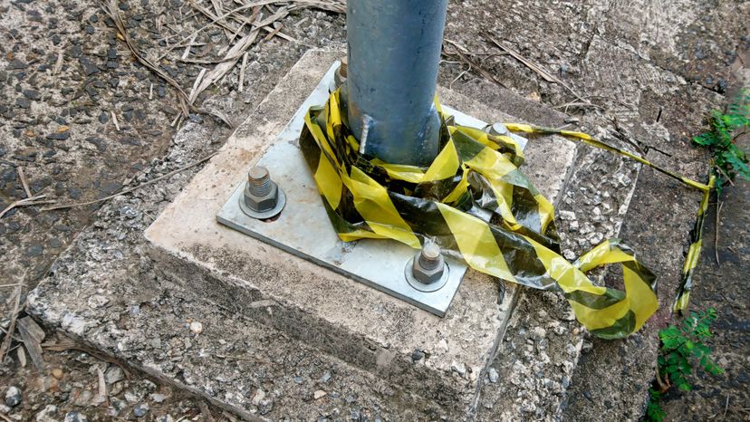 The base of a light pole, fixed to the floor with screws. 