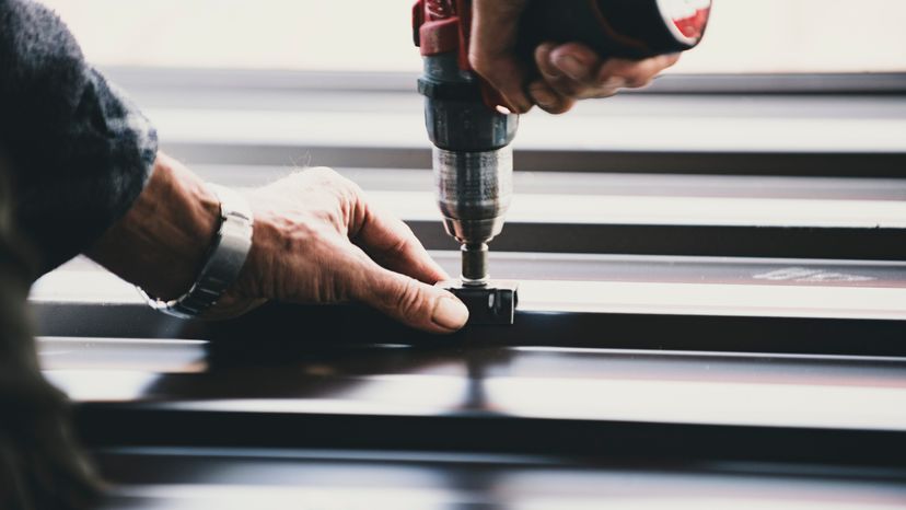 A building contractor installing metal roofing sheets. 