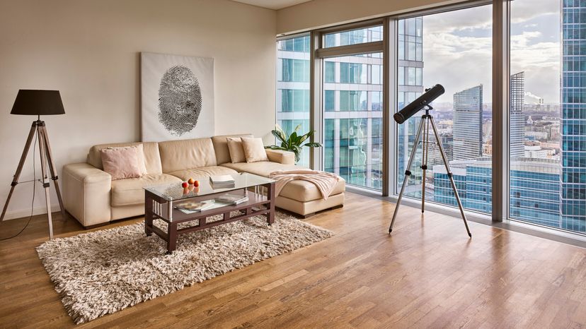 A telescope looking out an apartments glass wall. 