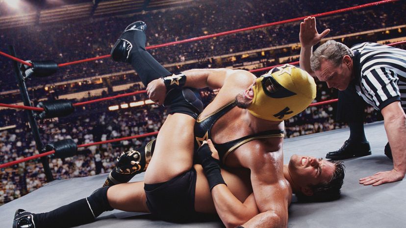 A wrestler holding another wrestler down while the referee counts down.