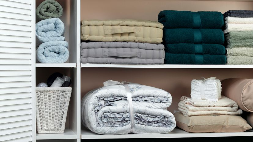 A linen closet with folded towels and clothes. 