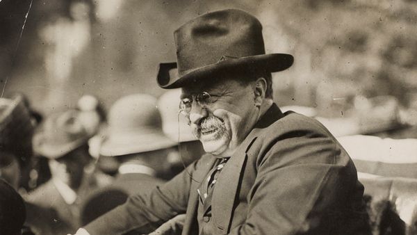 Men smiling outdoors in old-fashioned black and white.