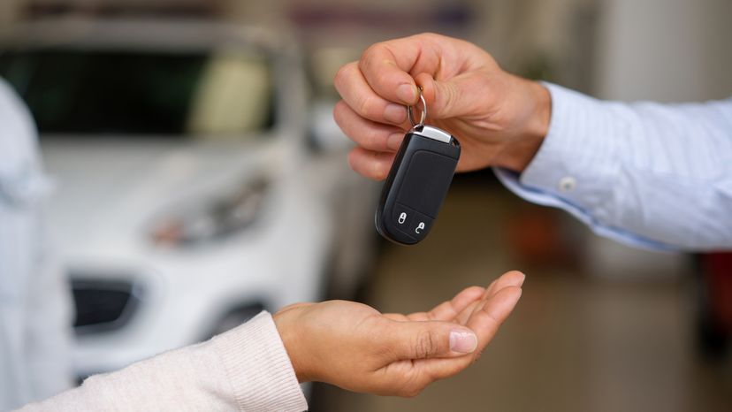 A car salesman handing over a car key to a buyer. 