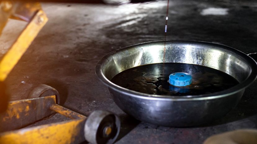 Old oil being drained out of an engine through the drain plug. 